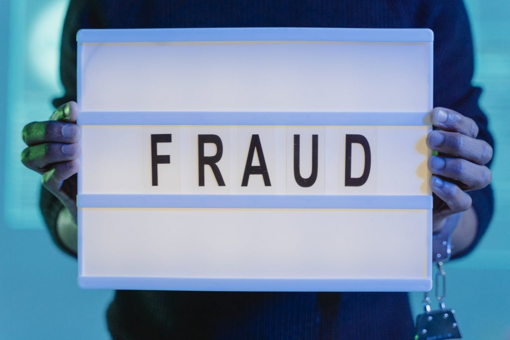 A person holding a sign with the word fraud referring to the fraud detection the Authorize.net payment gateway offers.
