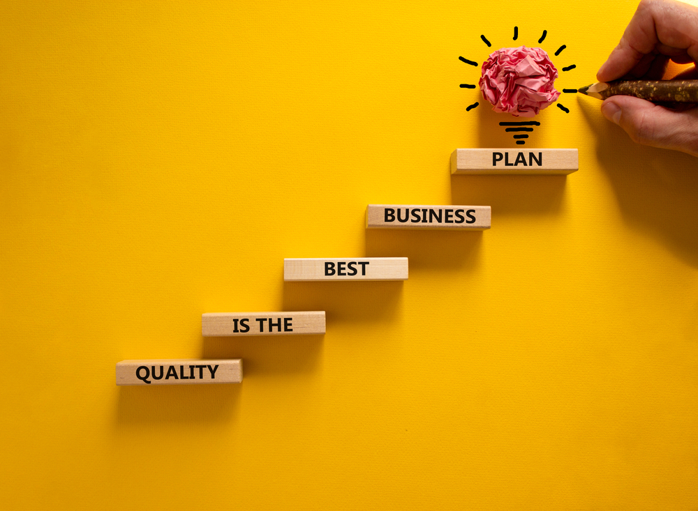 Business concept growth success process. Wood blocks stacking as step stair, yellow background, copy space. Businessman hand. Words 'quality is the best business plan'. Conceptual image of motivation.