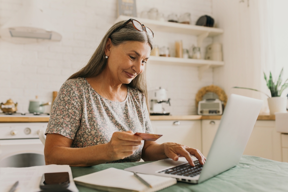 Happy senior woman making online payments of bill using laptop
