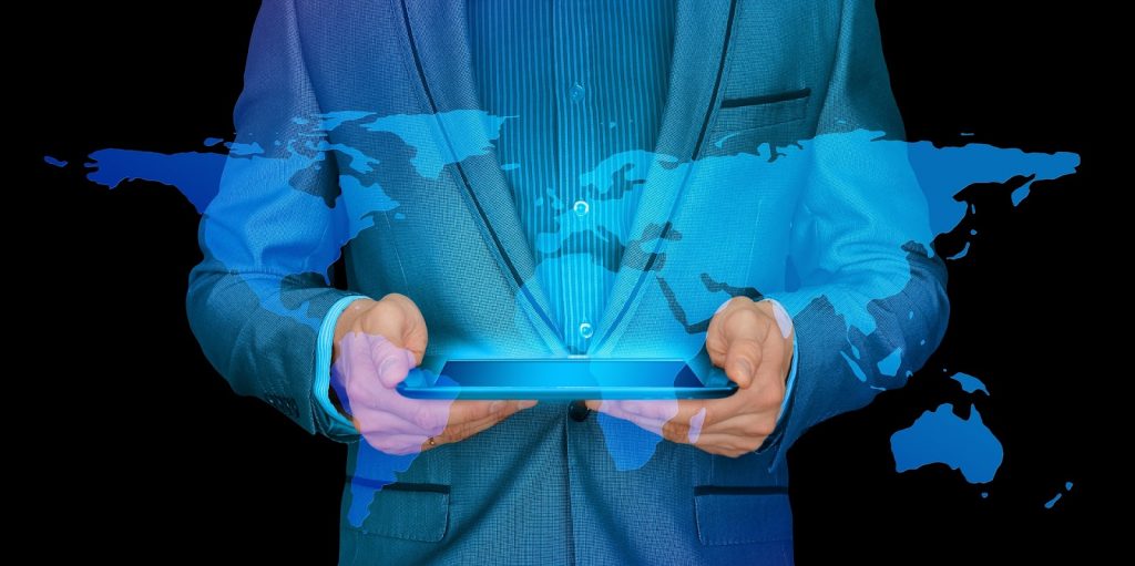 Man holding tablet with world map projected to symbolize why a business would need an international payment gateway